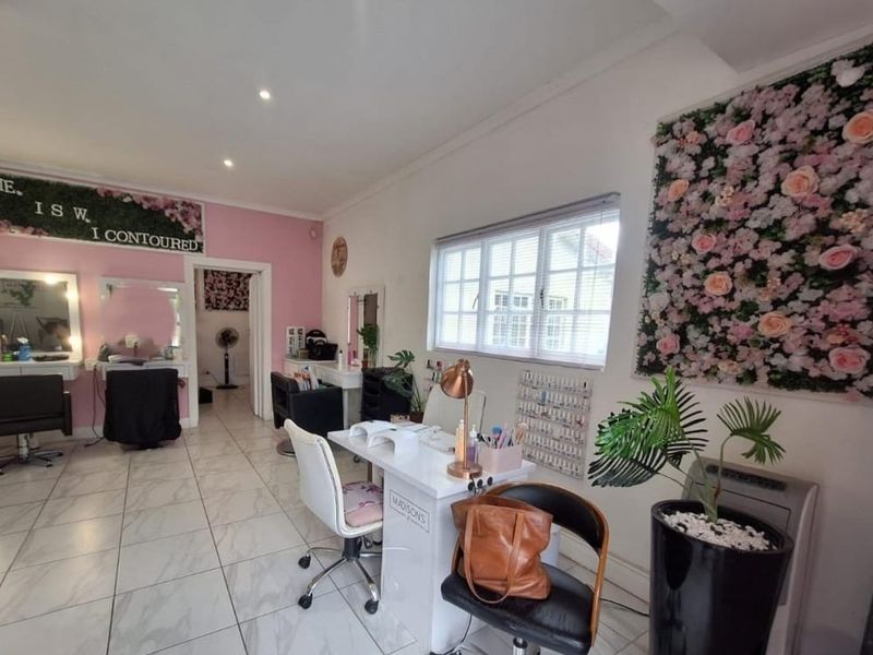 A commercial-style interior space featuring tiled flooring, recessed lighting, and large windows, currently utilized as a beauty salon.