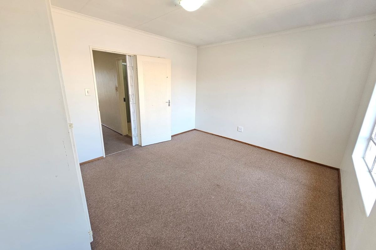 An empty bedroom featuring neutral walls, carpet flooring, and a ceiling light fixture, providing a blank canvas for potential updates.