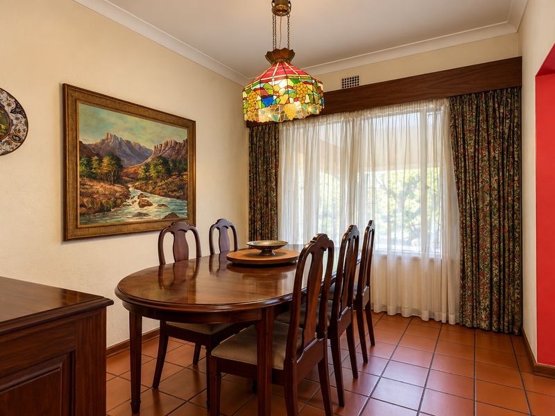 A traditional dining room featuring terracotta tiled flooring, cove cornicing, and a decorative stained glass pendant light fixture.
