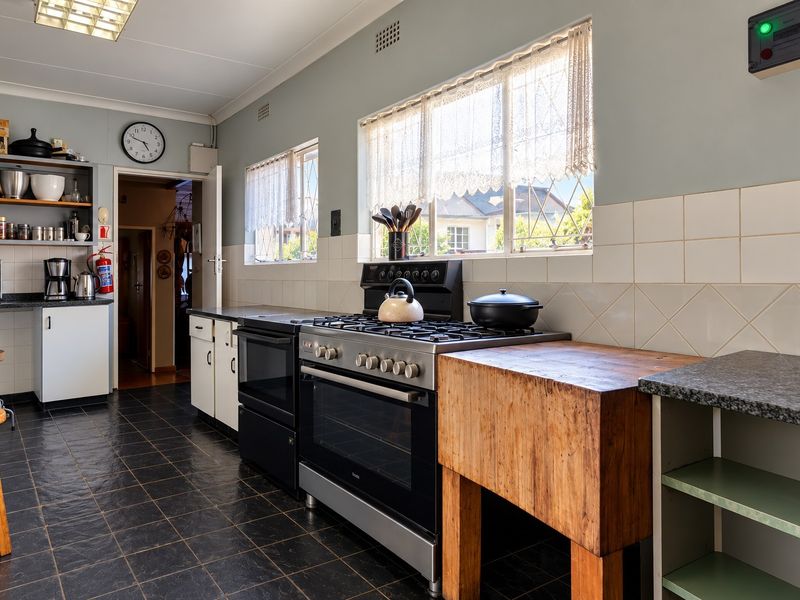 Functional kitchen featuring a gas stove, oven, butcher block prep area, tiled backsplash, and ample storage cabinetry with a classic layout.
