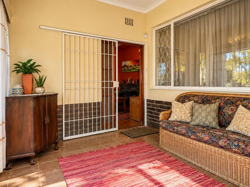 A covered patio area featuring tiled flooring, a brick base wall, and a sliding security gate leading into the main living space.