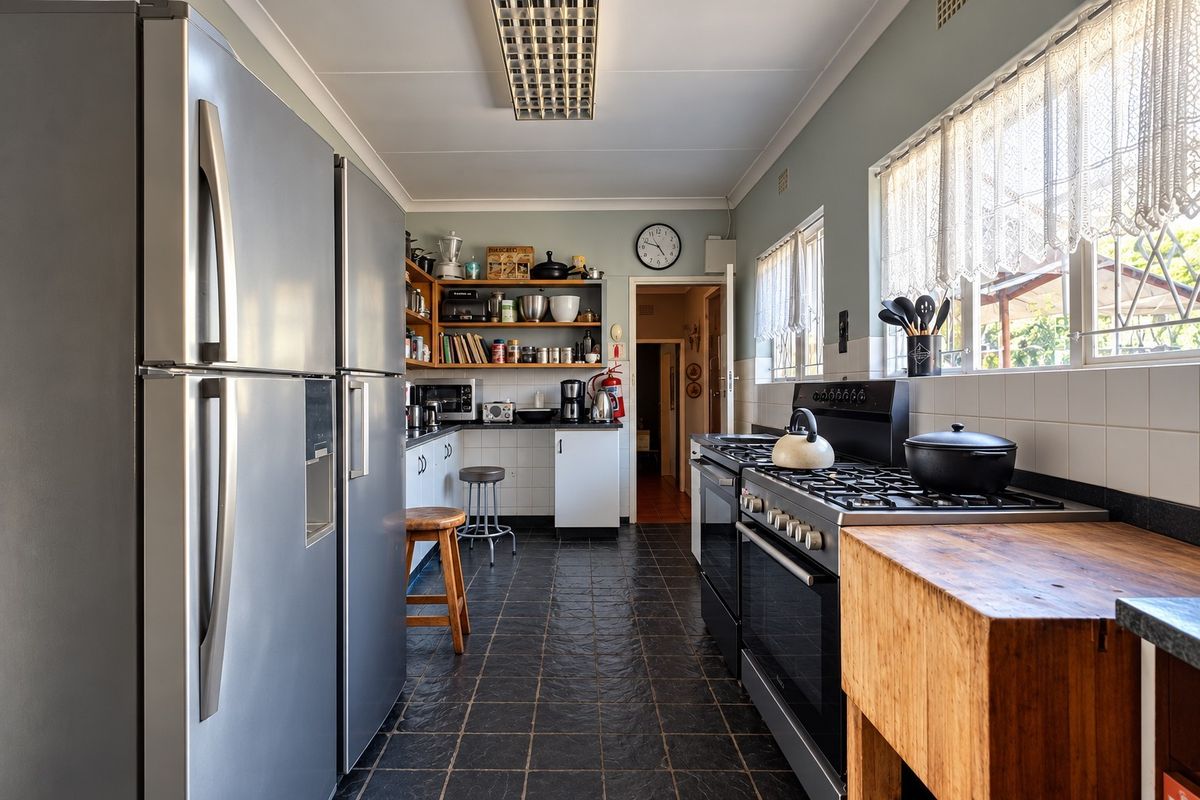 A functional kitchen featuring a gas stove, tiled backsplash, and ample built-in cabinetry with dark tiled flooring.