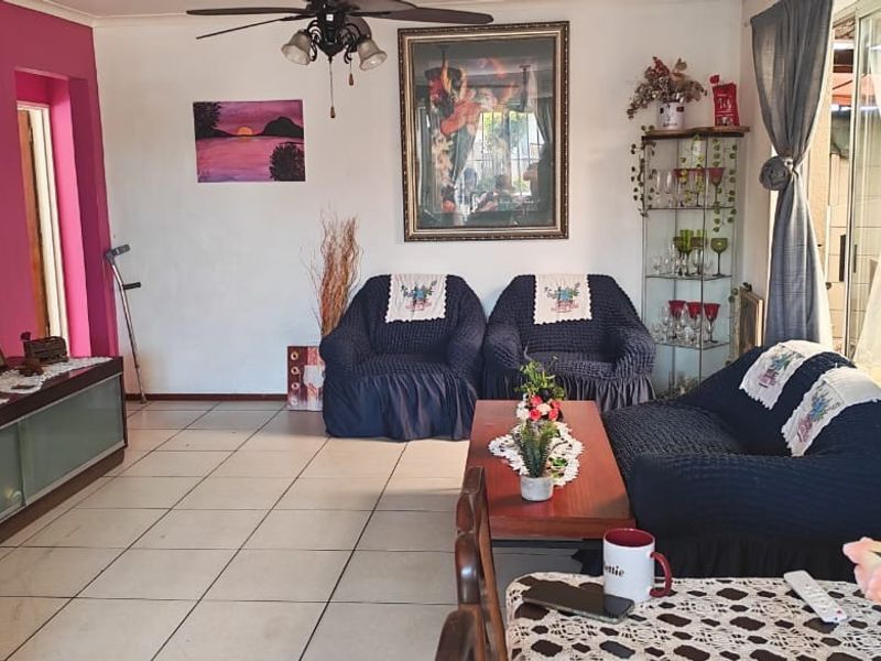 A living room featuring tiled flooring, a ceiling fan, and a sliding glass door providing access to the exterior.