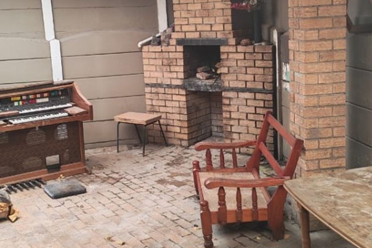 Covered outdoor patio area featuring a traditional brick built-in braai, brick paving, and exposed timber roof structure.