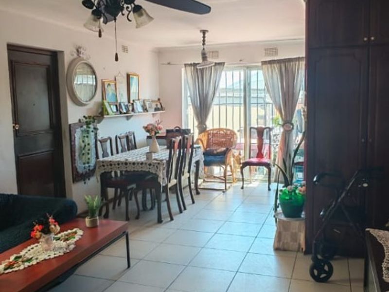 Open plan living and dining area featuring tiled flooring, a ceiling fan, and built-in cabinetry with access to the exterior via a sliding glass door.
