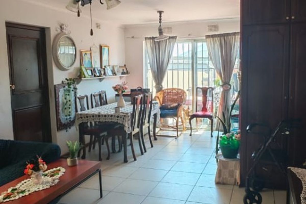 Open plan living and dining area featuring tiled flooring, a ceiling fan, and built-in cabinetry with access to the exterior via a sliding glass door.