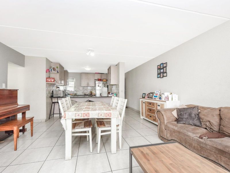 Open plan living and dining area featuring tiled flooring and an integrated kitchen with cabinetry and tiled backsplash.