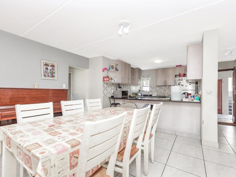 Open plan living and dining area featuring a functional kitchen with built-in cabinetry, granite countertops, and tiled flooring throughout.