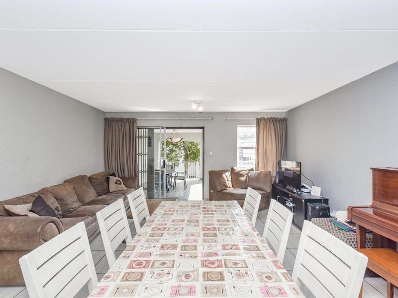 Spacious open-plan living and dining area featuring tiled flooring and direct access to an outdoor patio through a sliding glass door.