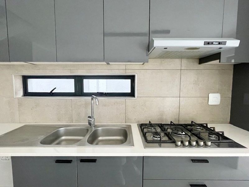 Modern kitchen featuring sleek grey cabinetry, stone countertops, a stainless steel double sink, and a built-in gas hob with an extractor fan.