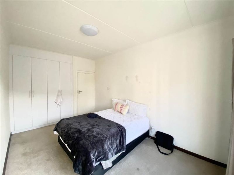 A bedroom featuring built-in cupboards, carpeted flooring, and a flush mount ceiling light. The room requires cosmetic updates to the walls and flooring.