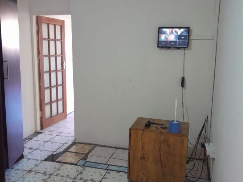 A functional hallway area featuring tiled flooring, a built-in cupboard, and a timber-framed glass door leading to an adjacent room.