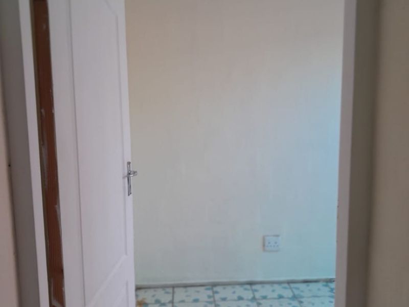An empty bedroom featuring tiled flooring and a standard internal door, presenting a blank canvas for renovation or interior design updates.