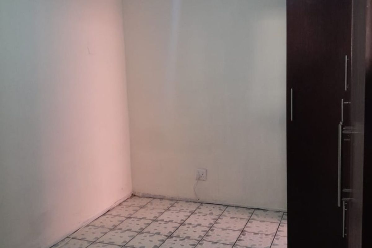 A simple, empty bedroom featuring tiled flooring and a built-in cupboard, providing a blank canvas for personalization.