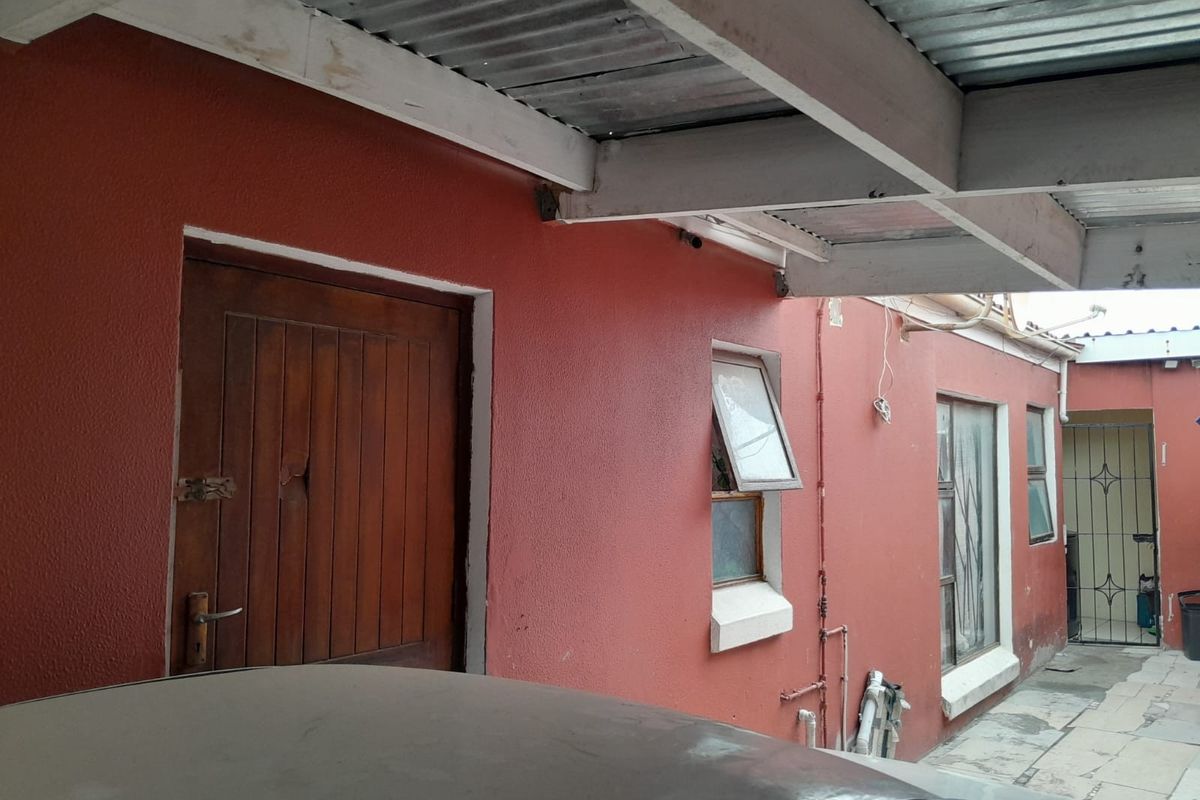 Rear exterior area featuring a covered patio space with timber beams, corrugated roofing, and access to the main dwelling via a timber door.