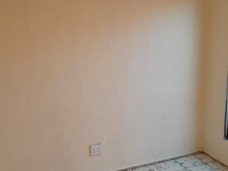 An empty bedroom featuring tiled flooring and plain walls, suitable for renovation or staging.