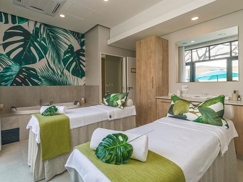 A well-appointed spa or treatment room featuring built-in cabinetry, a soaking tub, and modern recessed lighting with a tropical-themed feature wall.