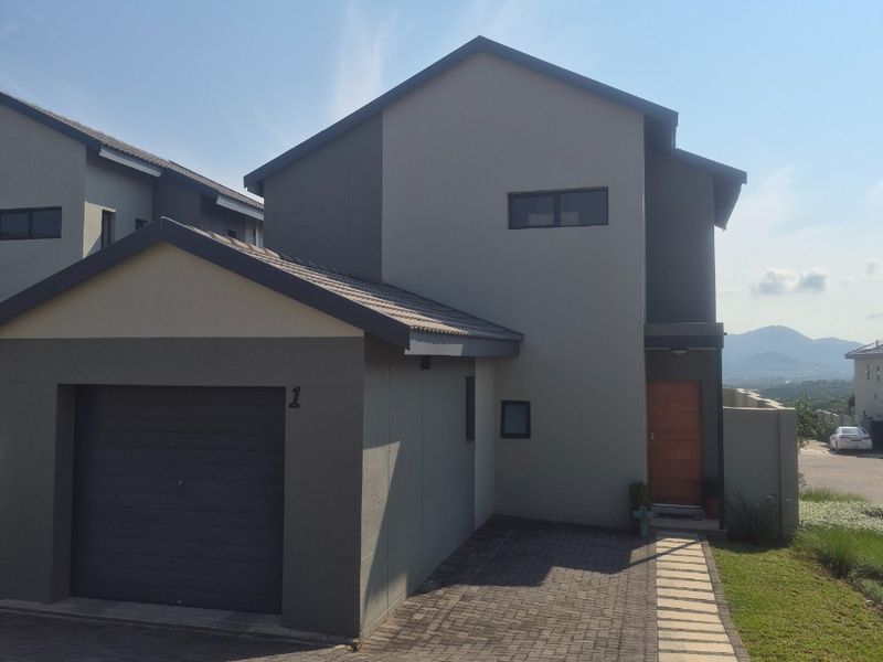 Modern townhouse exterior featuring a single garage, paved driveway, and a timber front door with a clean, contemporary facade.