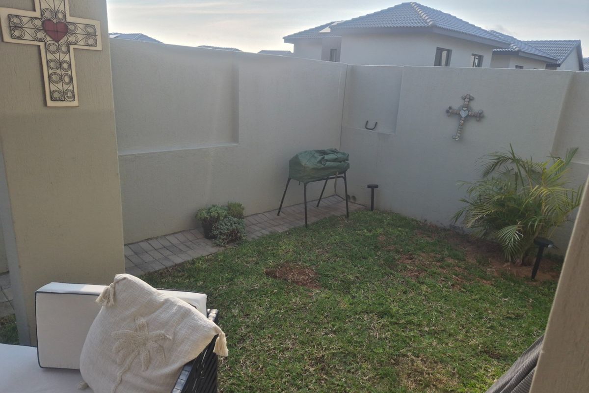 A private rear garden area featuring a small lawn, paved walkway, and high boundary walls for added privacy.