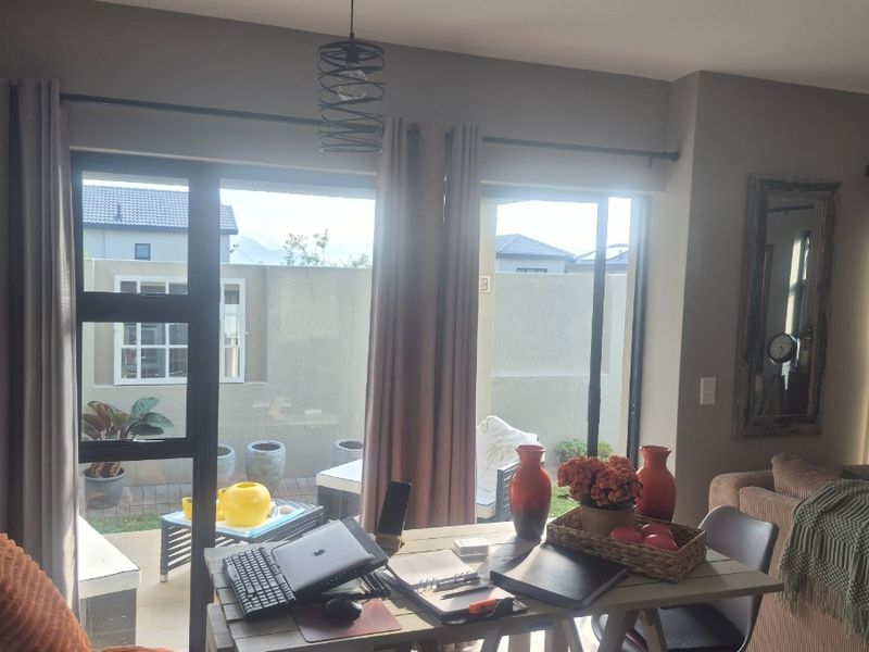 A bright living area featuring large sliding glass doors that provide direct access to the outdoor patio and garden space.