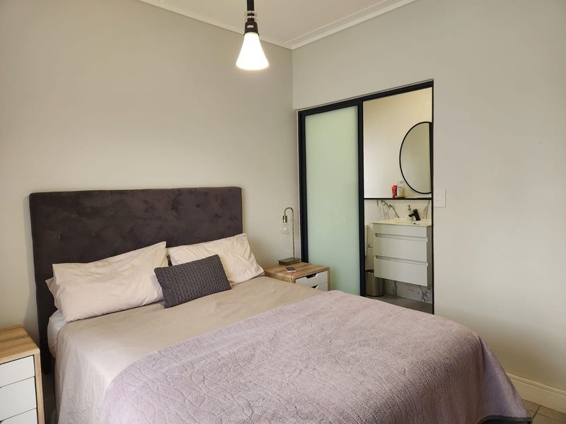A well-maintained bedroom featuring a modern en-suite bathroom with a sleek vanity, basin, and sliding door access.