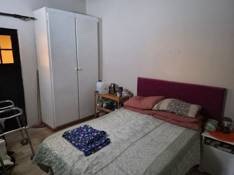 A functional bedroom featuring a built-in wardrobe and laminate flooring, offering a basic layout ready for cosmetic updates and modernization.