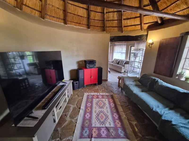 A rustic living room featuring a traditional thatched roof with exposed timber rafters and durable flagstone flooring.