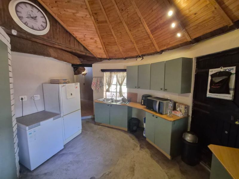 A rustic kitchen featuring built-in cabinetry, a double basin sink, and a distinctive exposed timber ceiling with a unique circular layout.