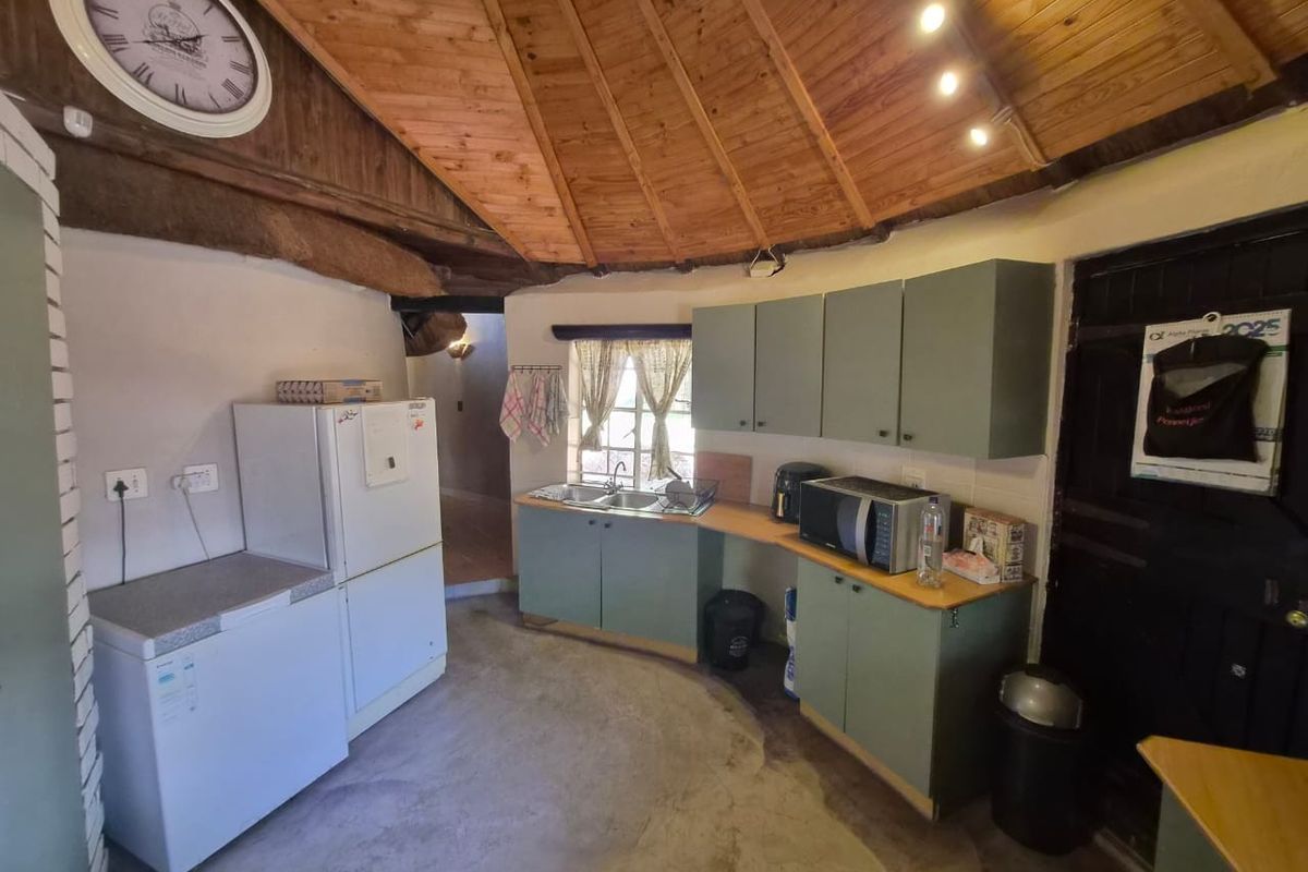 A rustic kitchen featuring built-in cabinetry, a double basin sink, and a distinctive exposed timber ceiling with a unique circular layout.