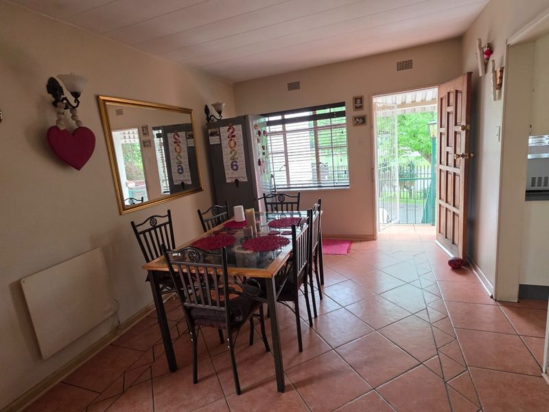 Dining area featuring tiled flooring, natural light from a window, and direct access to the exterior through a timber door.