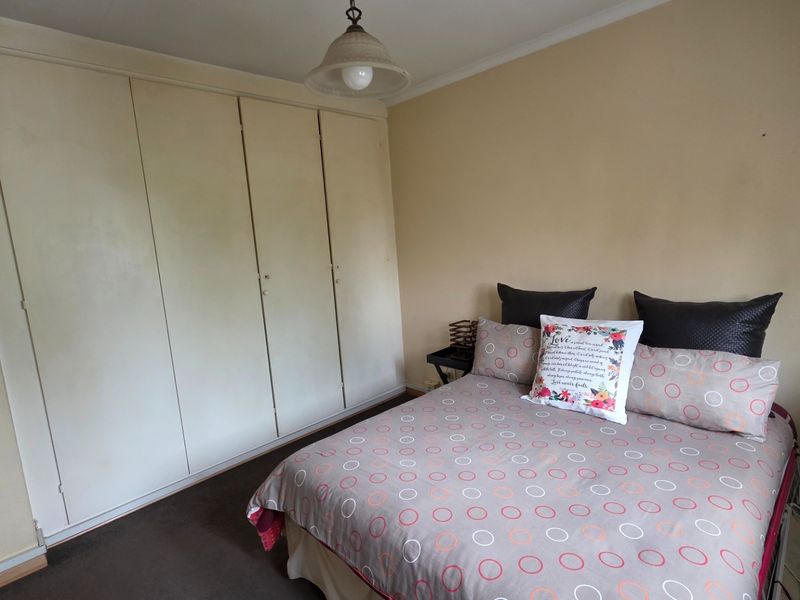 A bedroom featuring built-in cupboards and a pendant light fixture, with neutral wall tones and carpeted flooring.