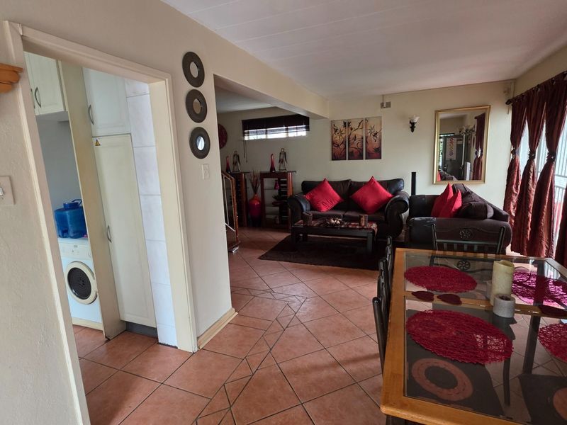 Open-plan living and dining area featuring tiled flooring, with an adjacent utility space visible through the doorway.