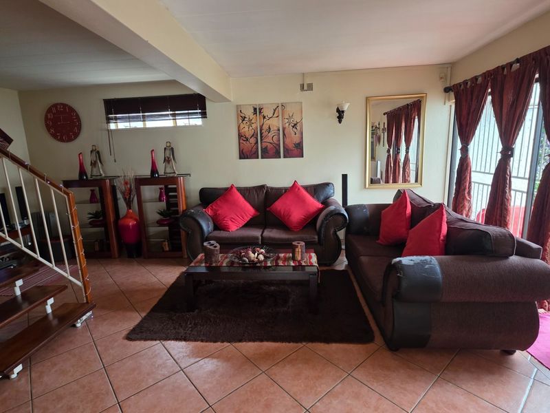 Spacious living room featuring tiled flooring, a wooden staircase, and large sliding glass doors providing access to the outdoor area.