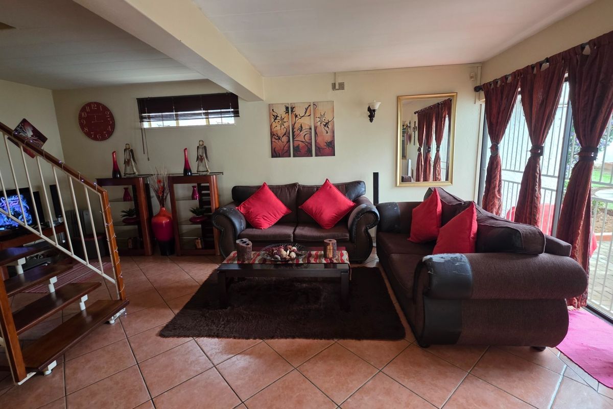 Spacious living room featuring tiled flooring, a wooden staircase, and large sliding glass doors providing access to the outdoor area.