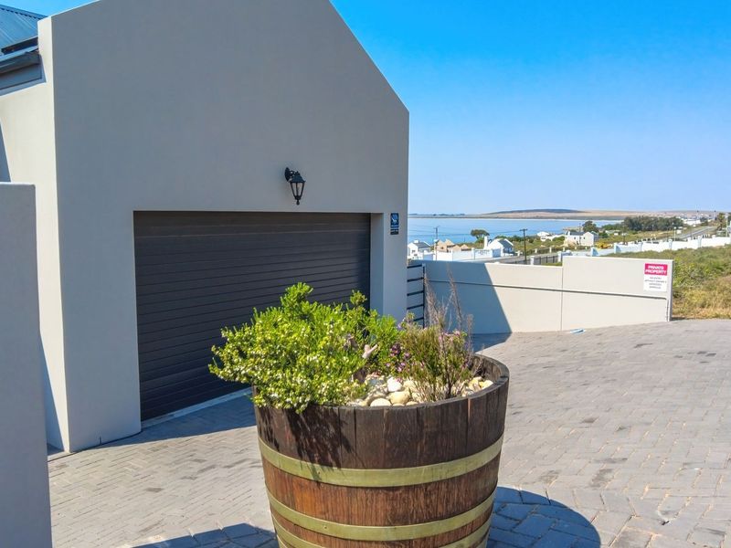 Front exterior view of the property featuring a paved driveway, garage entrance, and coastal views in the background.