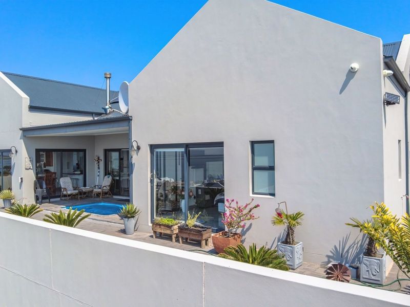 Rear view of the property featuring a paved patio area, a small swimming pool, and modern sliding glass doors leading into the home.