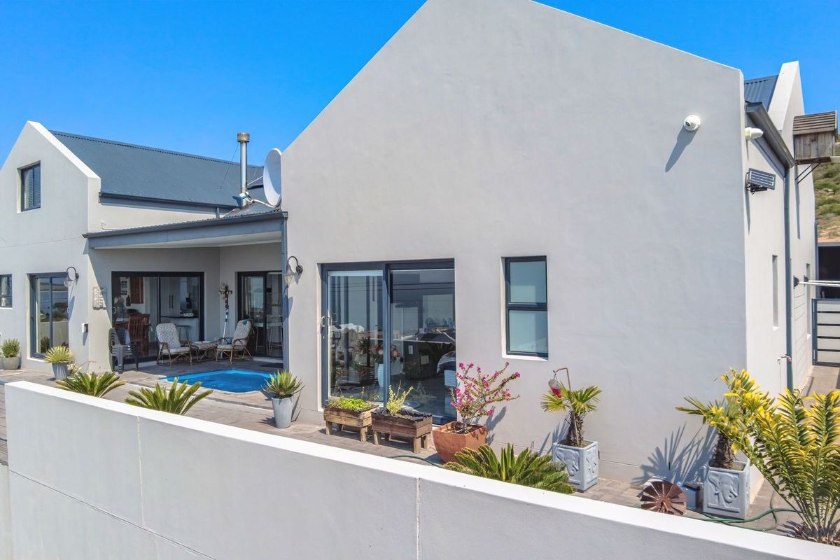 Rear view of the property featuring a paved patio area, a small swimming pool, and modern sliding glass doors leading into the home.