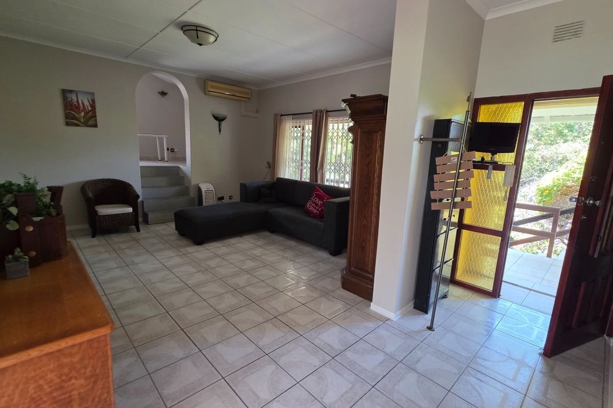 Spacious living room featuring tiled flooring, an air conditioning unit, and an arched entryway leading to an elevated area.