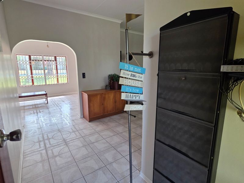 Entrance hall featuring tiled flooring and an arched doorway leading into the living area, with visible security gate on the window.
