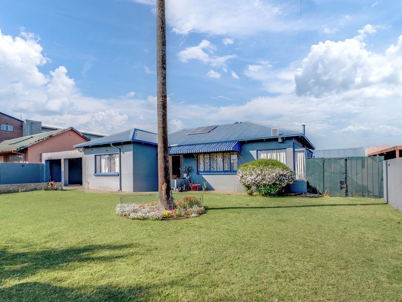 A view of the rear exterior of the house featuring a metal roof, solar panels, and a spacious lawn area.