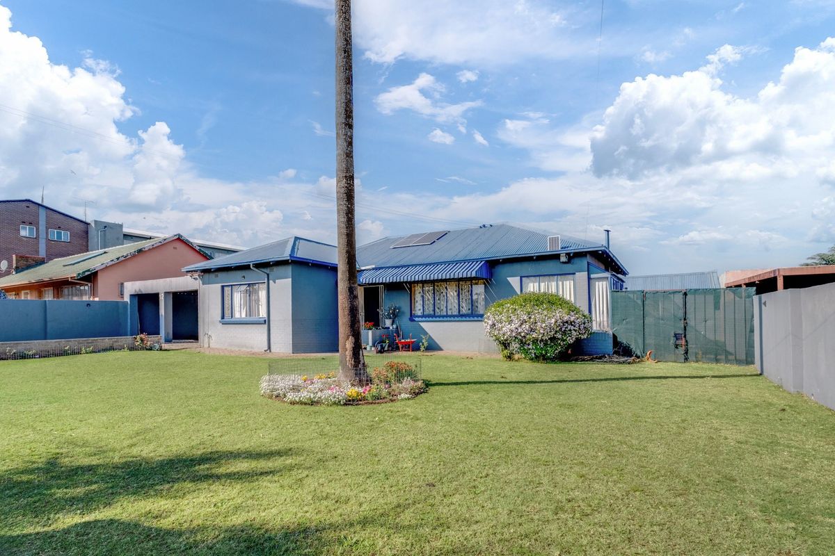 A view of the rear exterior of the house featuring a metal roof, solar panels, and a spacious lawn area.
