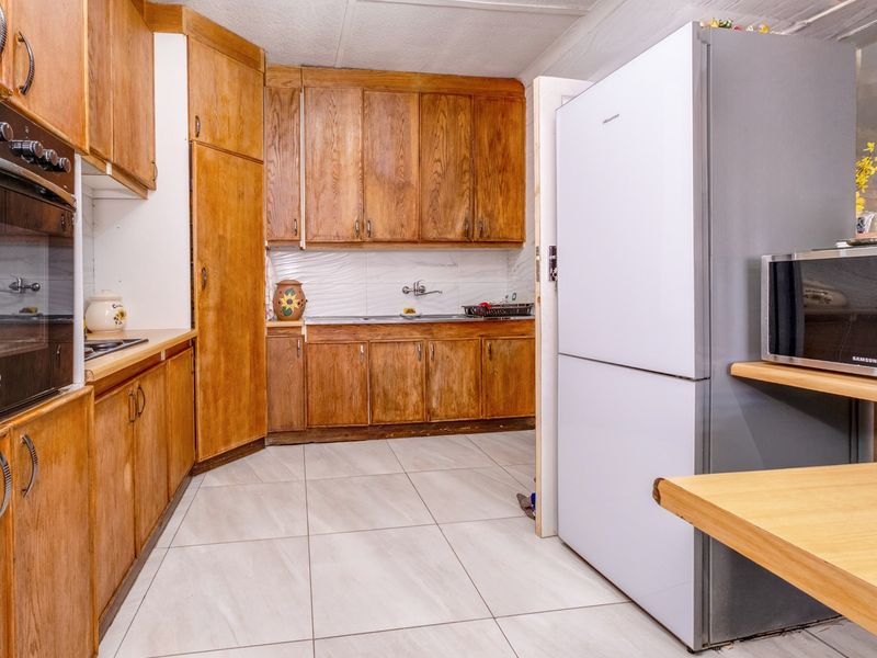 A functional kitchen featuring traditional wooden cabinetry, built-in oven, hob, and tiled flooring, offering a classic layout with ample storage space.