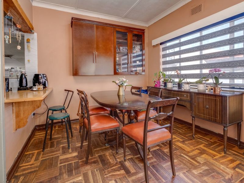 Dining room featuring classic parquet flooring, built-in wall cabinetry, and a breakfast bar counter, offering a functional space for meals.