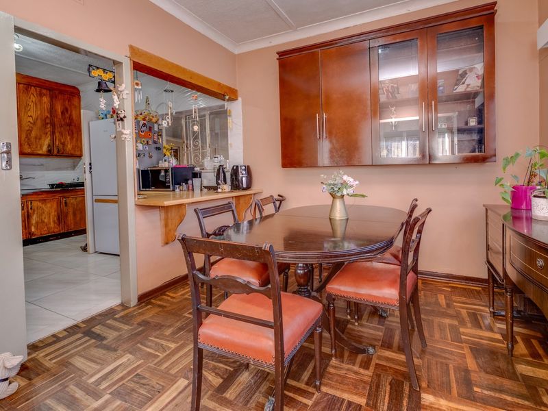 Dining room featuring classic parquet flooring, built-in wall cabinetry, and a convenient breakfast bar pass-through connecting to the adjacent kitchen area.