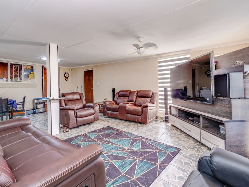 A spacious living room featuring tiled flooring, a ceiling fan, and neutral wall finishes, providing a comfortable and functional family living area.