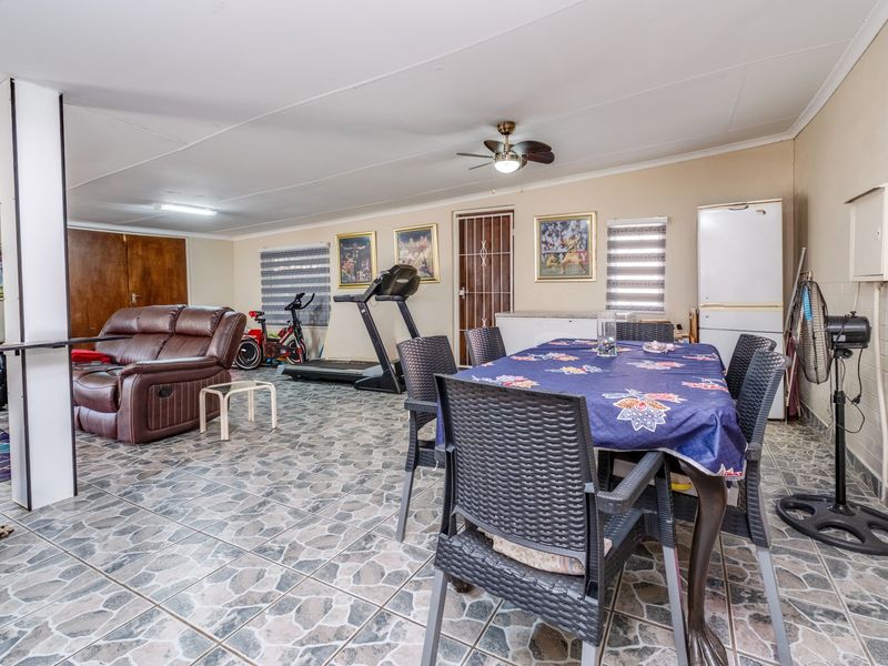 Spacious open-plan living and dining area featuring tiled flooring and a ceiling fan, offering a versatile layout for family living.