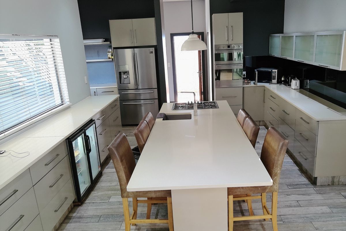 Modern kitchen featuring a large central island with a gas hob, quartz countertops, integrated appliances, and sleek cabinetry with recessed lighting.