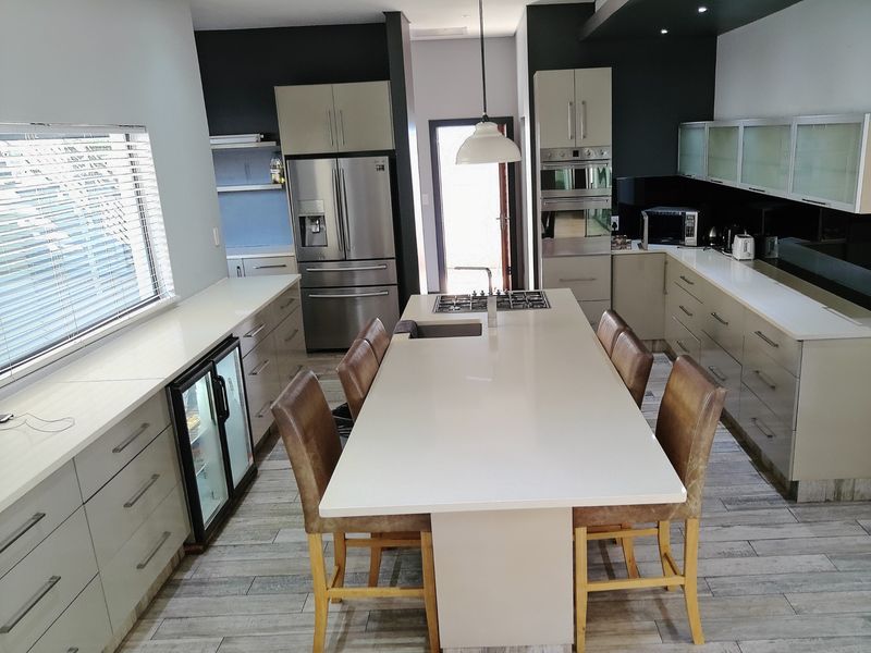 Modern kitchen featuring a large central island with a gas hob, quartz countertops, integrated appliances, and sleek cabinetry with recessed lighting.