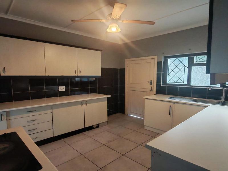 A functional kitchen featuring ample built-in cabinetry, laminate countertops, a stainless steel sink, and ceramic tile finishes throughout.