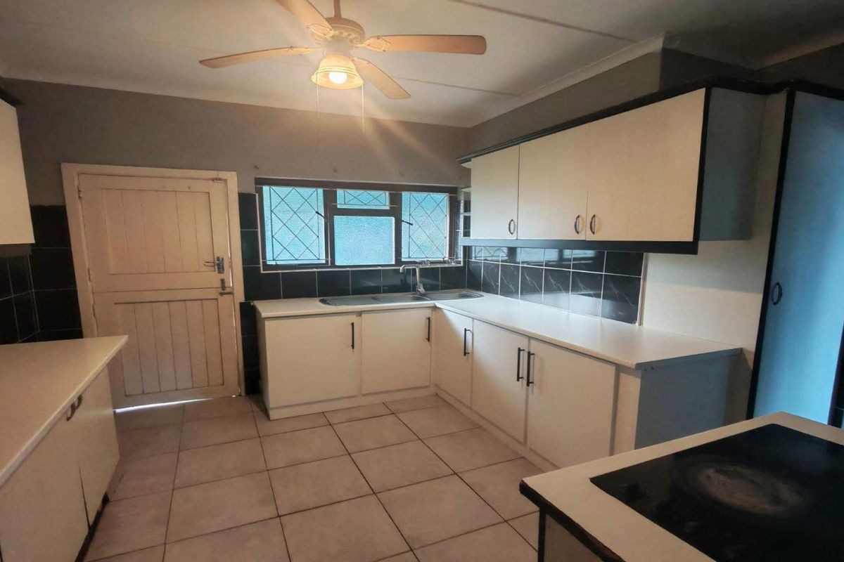A functional kitchen featuring white built-in cabinetry, tiled flooring, a tiled backsplash, and a ceiling fan, offering a clean and practical workspace.